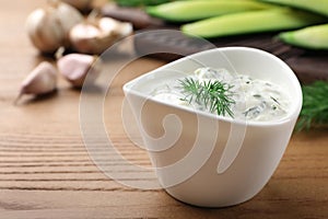 Cucumber sauce and ingredients on wooden background, space for text.