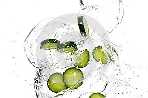 Cucumber slices and tomato, onion, fallen in water on a white background, top view