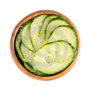 Fresh salad cucumber with skin, diagonally sliced, in a wooden bowl photo
