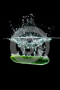 Cucumber splashing water isolated onblack background. Healthy food