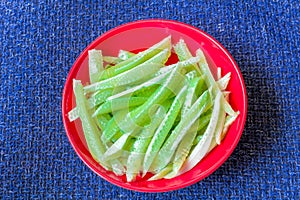 Cucumber strips on scarlet plate on dark blue background