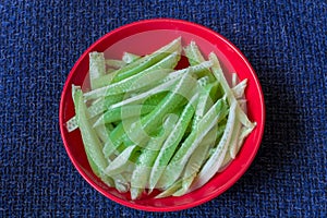 Cucumber strips on scarlet plate on dark blue textile background