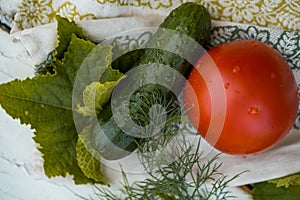cucumber and tomato and dill on a linen napkin with embroidery. Fresh vegetables from the garden. leaves of greenery.