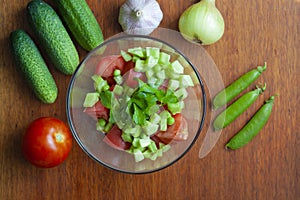 Cucumber and tomato salad in a bowl, ripe vegetables on the table