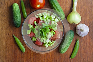 Cucumber and tomato salad in a bowl, vegetables on the table