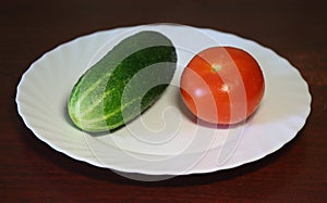 Cucumber and tomato are on a white plate