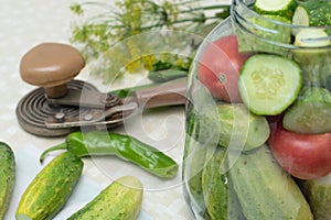 Cucumbers with green hot pepper on the table with glass jar with pickled vegetables cucumber and tomato with herbs and