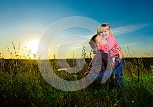 Cuddling children in a field at sunset love