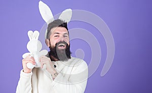 Cuddly bunny. Symbolizing spring, new life and fertility. Bearded man in easter rabbit costume holding hare toy. Happy