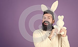 Cuddly bunny. Symbolizing spring, new life and fertility. Bearded man in easter rabbit costume holding hare toy. Happy