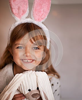 Cuddly companion. Portrait of an adorable little girl wearing bunny ears and holding her toy rabbit.