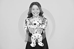 Cuddly dog. Happy small girl hold toy dog yellow background. Little schoolchild smile with soft dog. Adorable dog pet