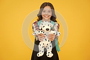 Cuddly dog. Happy small girl hold toy dog yellow background. Little schoolchild smile with soft dog. Adorable dog pet