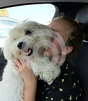 Cuddly hug of a girl and her pet in a car