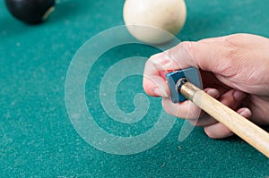 Cue stick with chalk block on green billiard table.Chalk block on pool table