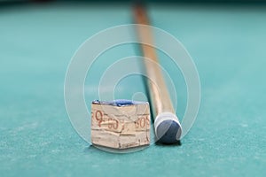 A cue stick and a chalk on a pool table