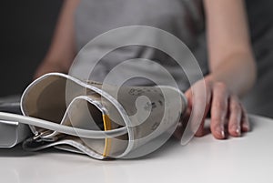 Cuff of medical tool for blood pressure measuring closeup and female hand on table