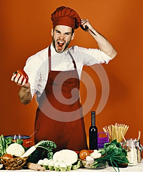 Cuisine and professional cooking concept. Cook works in kitchen near vegetables and tools