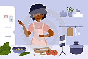 Culinary video broadcast with black woman cooking on kitchen and making content by smartphone