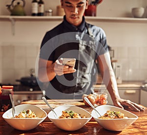 The culinary wiz strikes again. Shot of a young man using a smartphone to take pictures of a healthy meal he prepared at