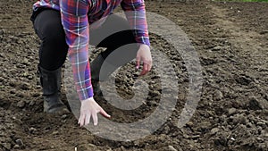 Cultivated land. Farmel strokes the black earth with his hands. A farmer in boots on black soil checks the soil for growing