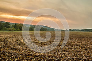 Cultivation of the autumn field with orange sky