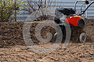 The cultivator digs the earth, clods of earth fly out from under the cultivator