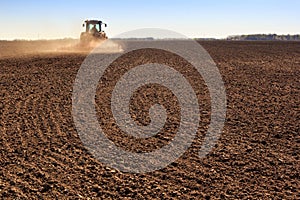 cultivator operates on ploughed field makes dust