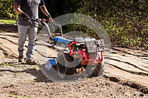 Rototiller tractor unit preparing soil dirt on outdoor garden photo