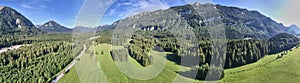 Cultural landscape in the Alps with meadows and pastures between high mountains and hills, composite panorama