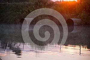 Culverts In Pond At Sunrise With Reflection photo