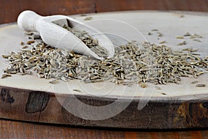 Cumin seed and wooden scoop on board Cuminum cyminum