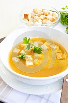 Cumin soup served in a white dish with croutons and parsley