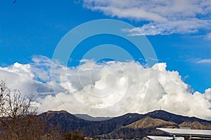 Cumulos, nimbus, clouds with angeles crest mountains, blue sky, sunlight,  solar panels photo