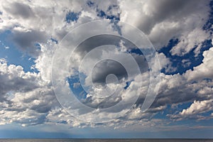 Cumulus clouds against the blue sky above the sea