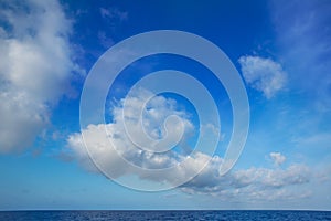 Cumulus clouds in blue sky over water horizon