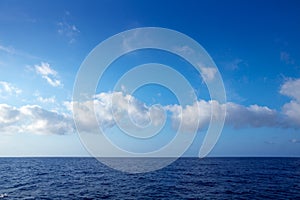 Cumulus clouds in blue sky over water horizon