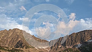 Cumulus clouds float over rocky ridge in blue sky