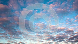 Cumulus clouds fly fast across the blue sky at sunset, time-lapse