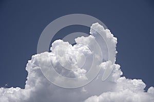 Cumulus congestus cloud. A single white clouds with sharp edges under a blue sky