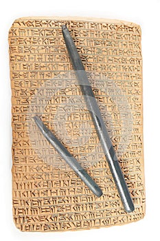 Cuneiform written in brown clay with rest of sand dirt and wooden writing tools