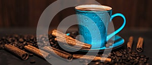 Cup of aromatic black coffee, coffee beans and cinnamon sticks on dark background. Still life. Panoramic banner.