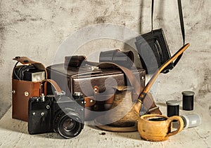 A cup of aromatic coffee. Old film cameras, photographic film, leather case for photographic equipment. Old photographic equipment
