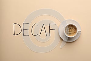 Cup of aromatic coffee and word Decaf on beige background