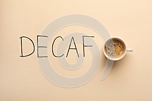 Cup of aromatic coffee and word Decaf on beige background, top view