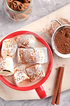 Cup of aromatic hot chocolate with marshmallows, cocoa powder and cinnamon sticks on table, flat lay