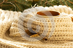 Cup of autumn coffee, tea or hot chocolate, fall leave on a warm scarf. Drink for autumn cold rainy days. Seasonal