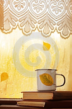 Cup of autumn tea, coffee, chocolate and yellow leaves on rainy window, copy space. Hot drink for autumn mood.