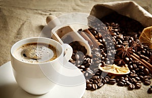 Cup and bag full of coffee beans,dried oranges on linen