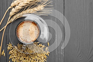 Cup of barley coffee, grains and spikes on gray wooden table, flat lay. Space for text